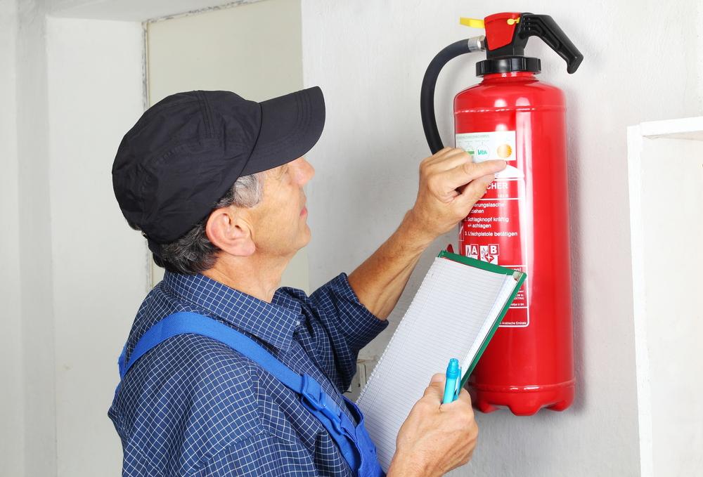 Homem conferindo extintor de incêndio, evitando riscos